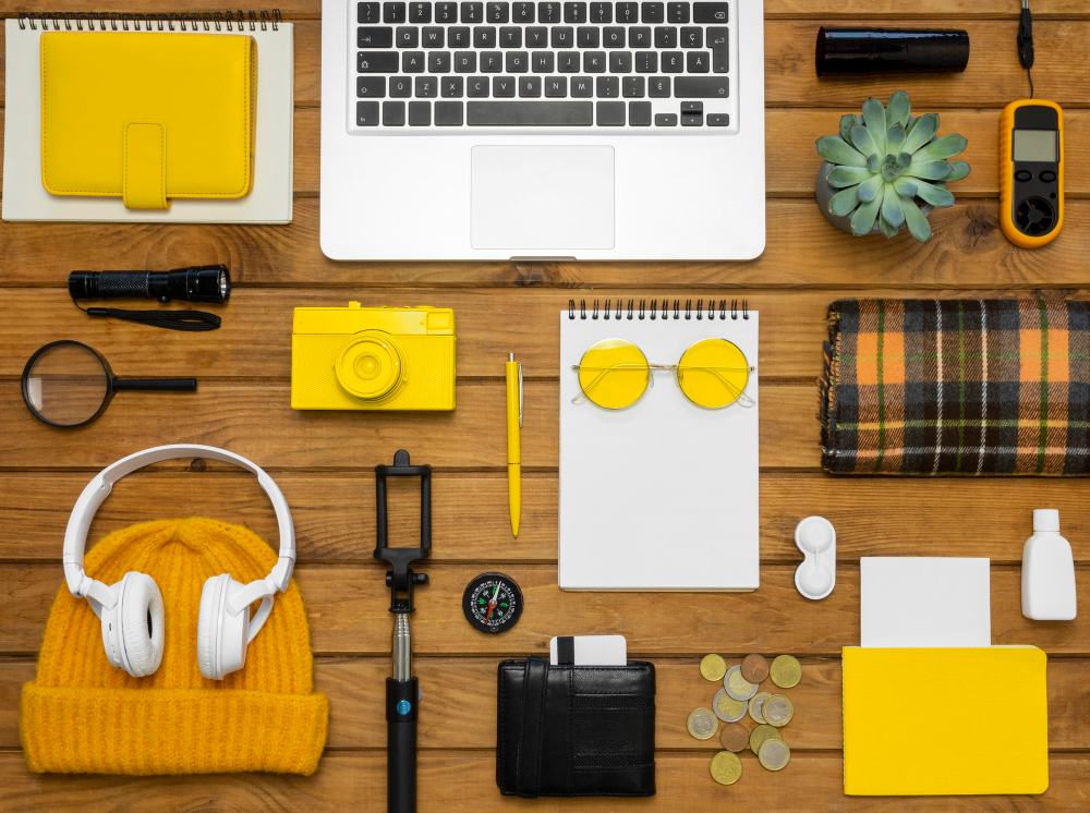 yellow color objects with different objects like laptop ,pen cap,copy on a table 